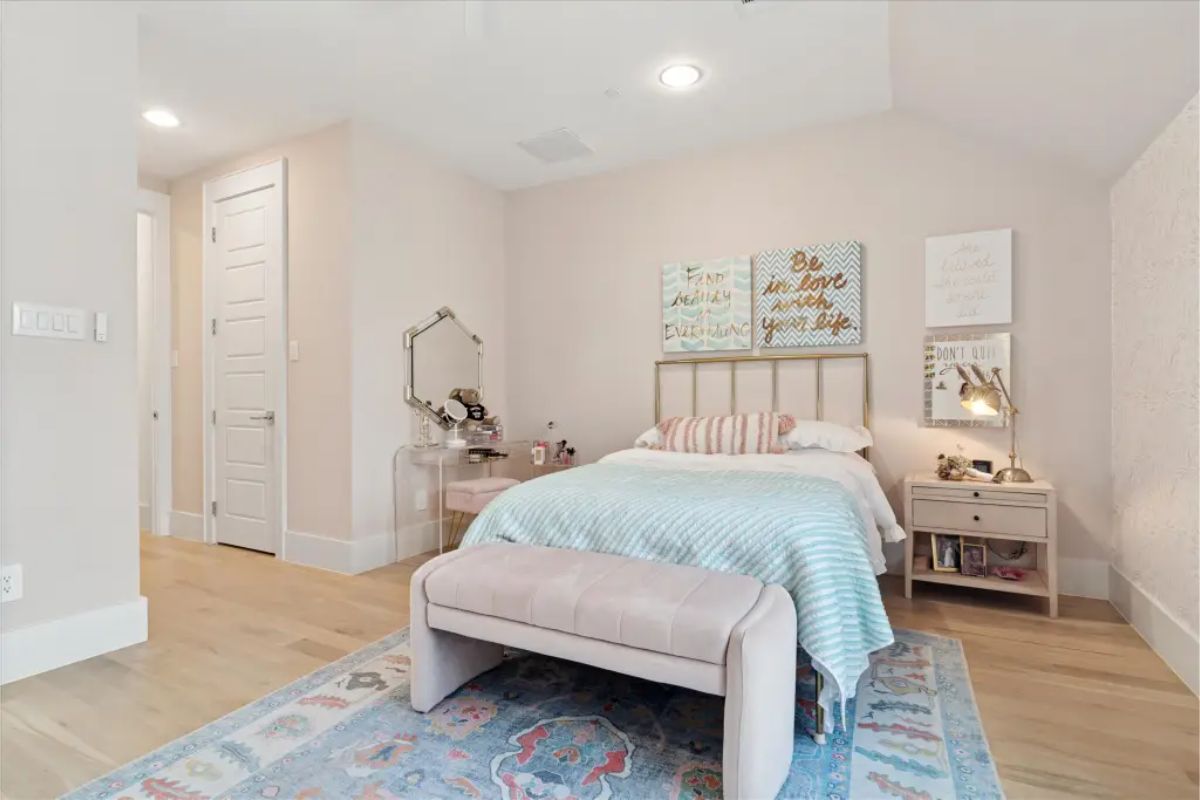 Bedroom with upholstered bed, bench, and pastel accents. 