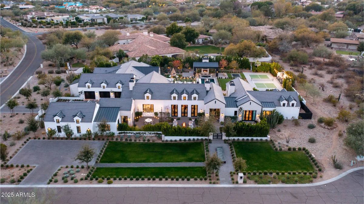 Multi-wing estate with gray tile roofing, dormer windows, dual gated entrances, and expansive backyard featuring a pool, sport courts, and multiple outdoor living areas.