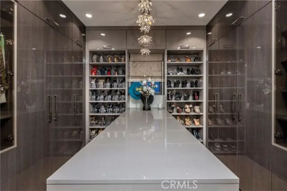Expansive walk-in closet with central island, glass cabinetry, and floor-to-ceiling shelving. 