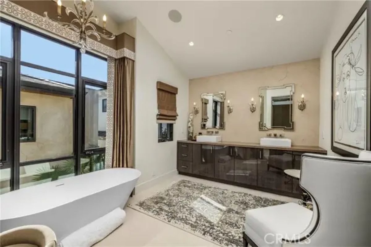Primary bathroom with freestanding tub, double vanity, and floor-to-ceiling windows. 