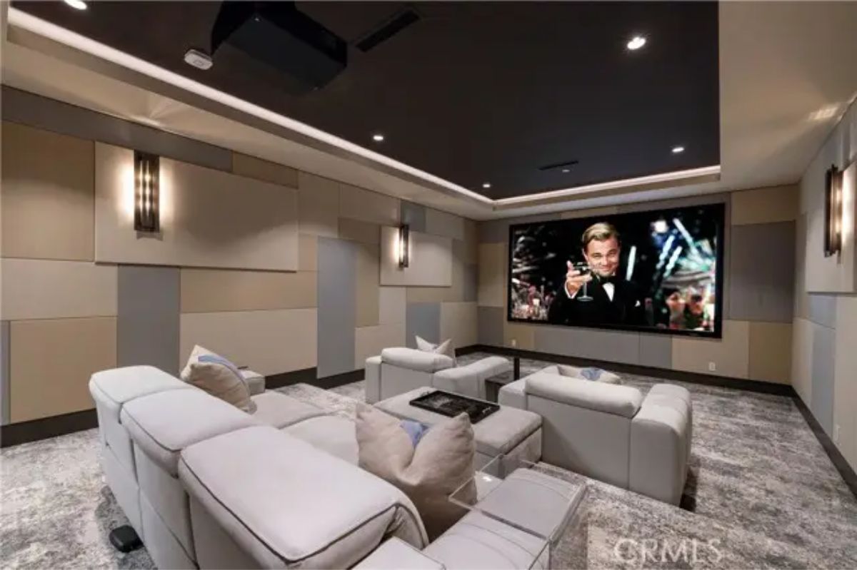 Home theater with tiered recliners, wall sconces, and large projection screen. 