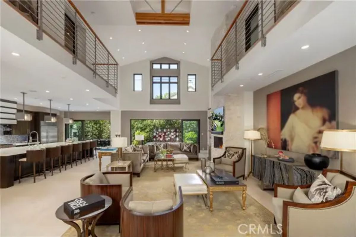 Spacious living area with vaulted ceiling, large portrait, and open kitchen with bar seating. 