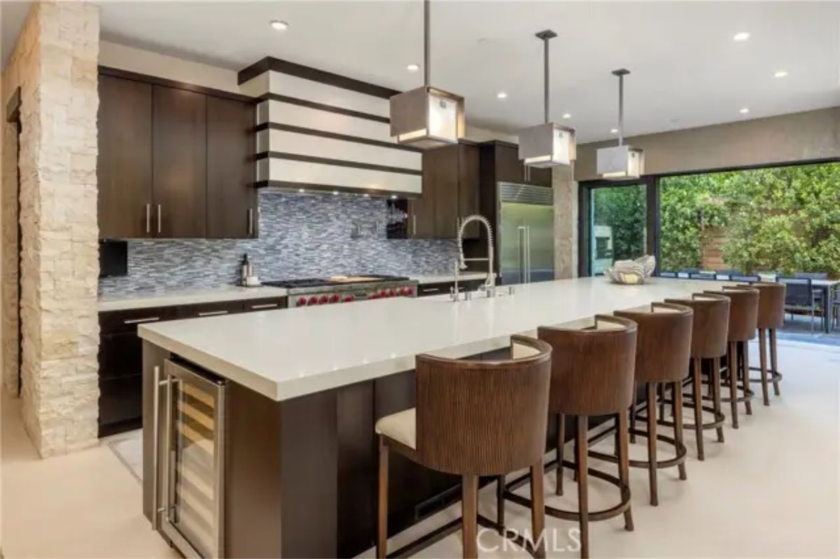 Modern kitchen with oversized island, pendant lighting, and sliding glass doors to outdoor space. 
