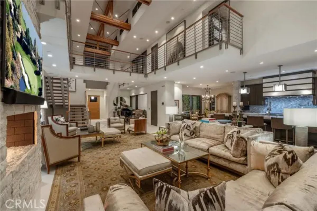 Alternate angle of open-concept living area with coffered ceiling and visible staircase. 