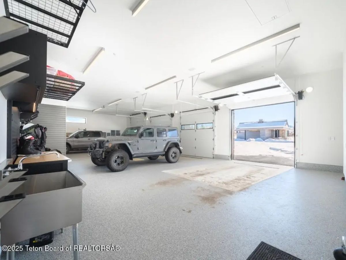 Spacious garage with epoxy flooring, built-in storage, and multiple vehicles. 