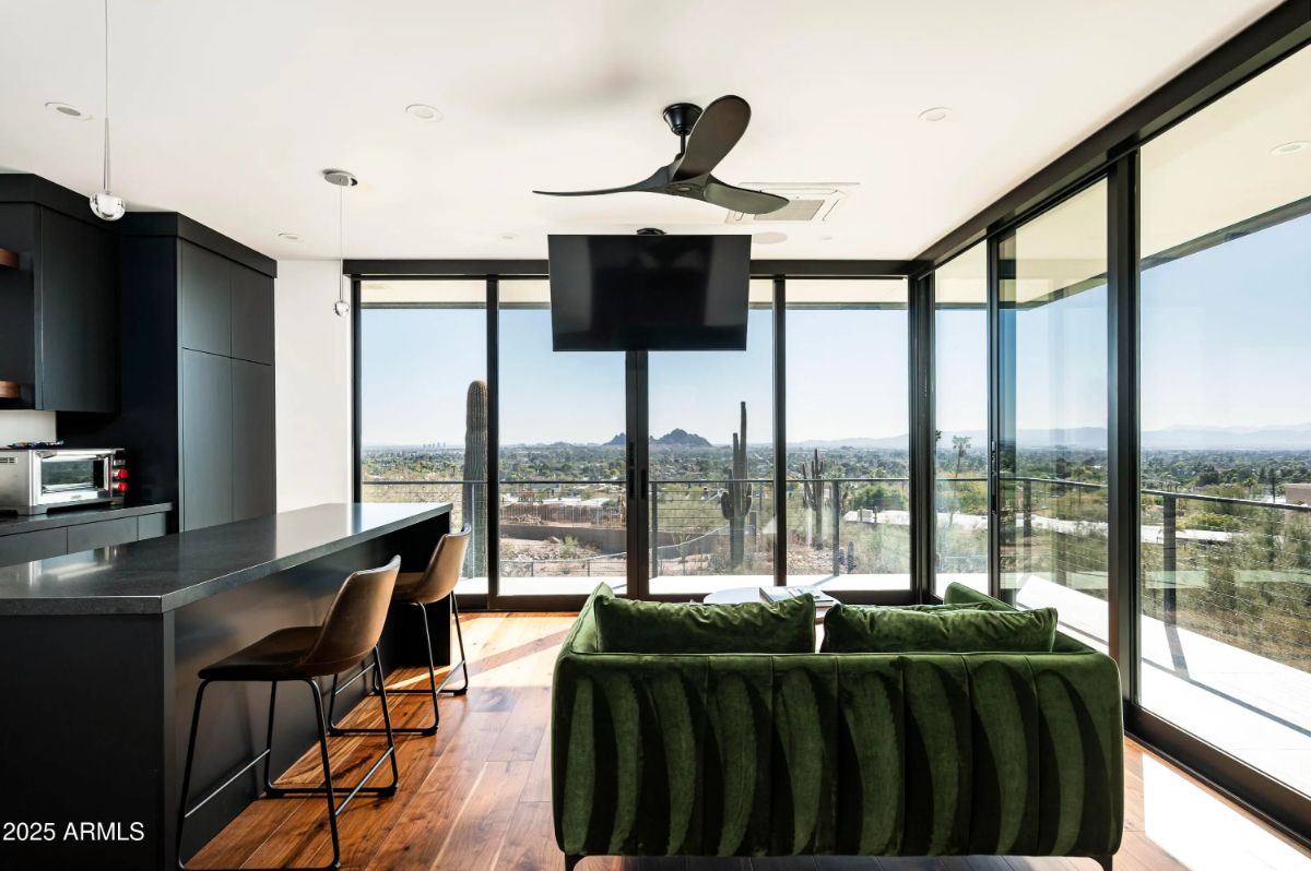 Glass-wrapped sitting area with panoramic views and a compact kitchen counter. 