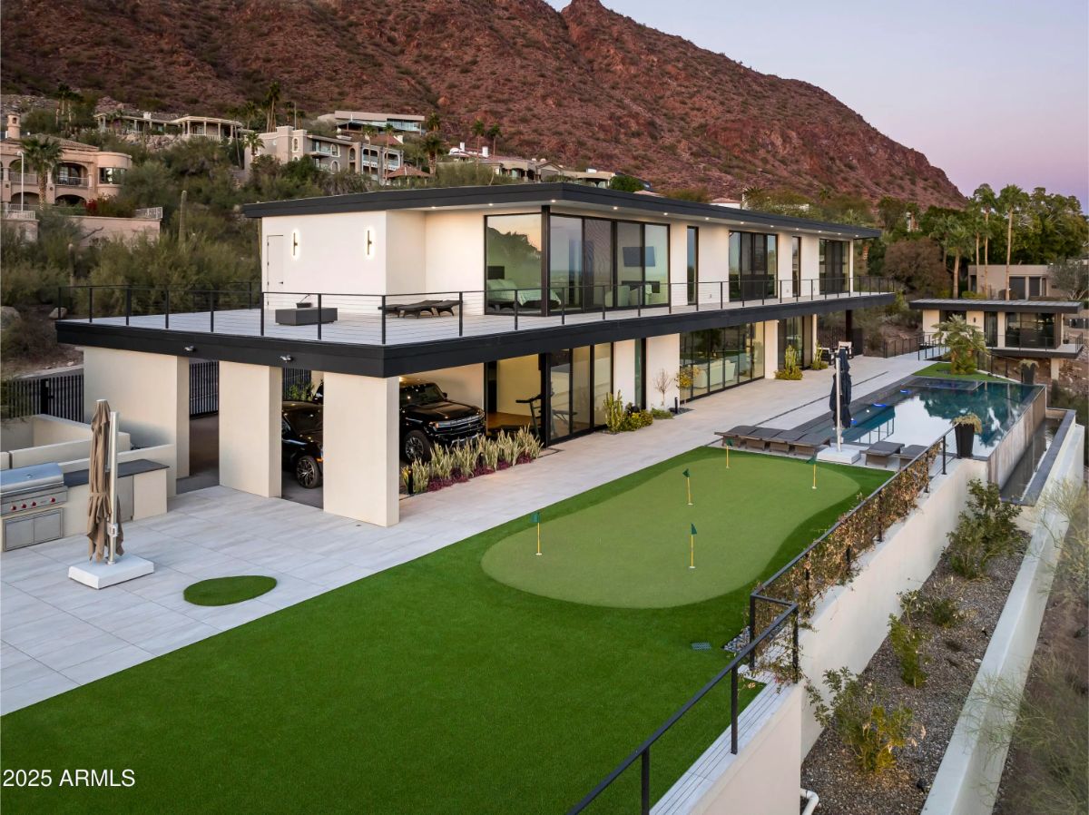 Hillside exterior with modern design, rooftop turf, and swimming pool along one side. 