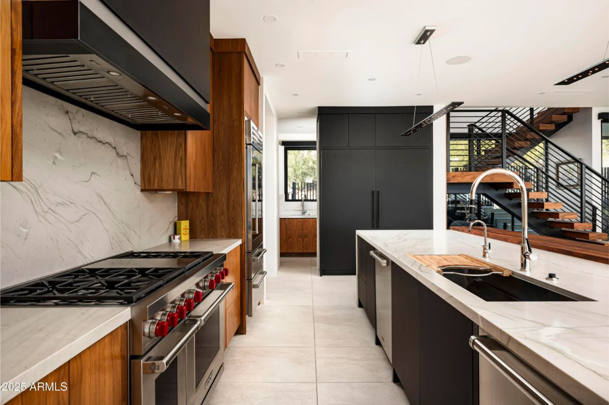 Chef’s kitchen with dual-tone cabinetry, marble backsplash, large island, and commercial-grade appliances. 