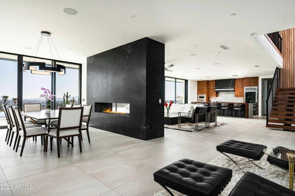 Bright open-concept space with a central black fireplace separating dining and living areas. 