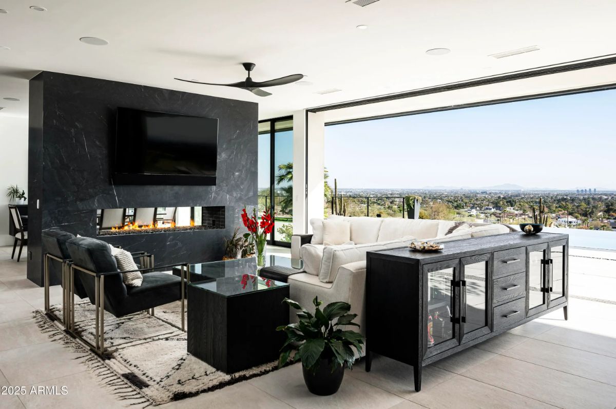 Modern living room with black feature wall, double-sided fireplace, and full-width glass opening. 