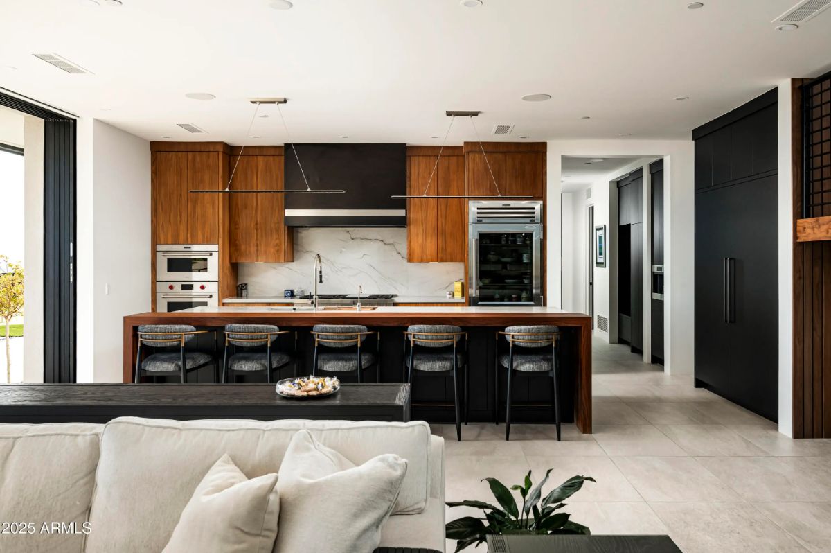 Kitchen with waterfall island, wood cabinetry, and integrated appliances in a sleek, open layout. 