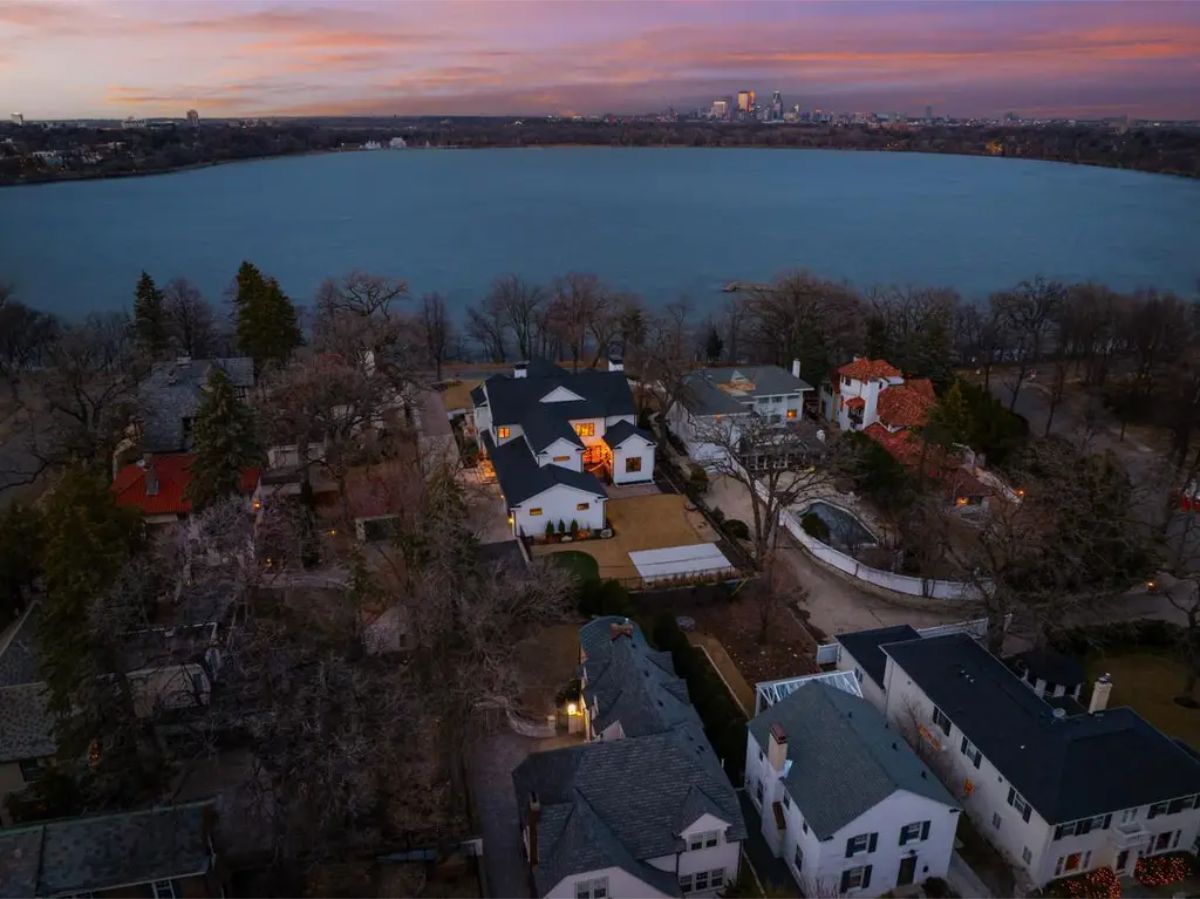 Aerial view of lakeside neighborhood at sunset with city skyline in the distance. 