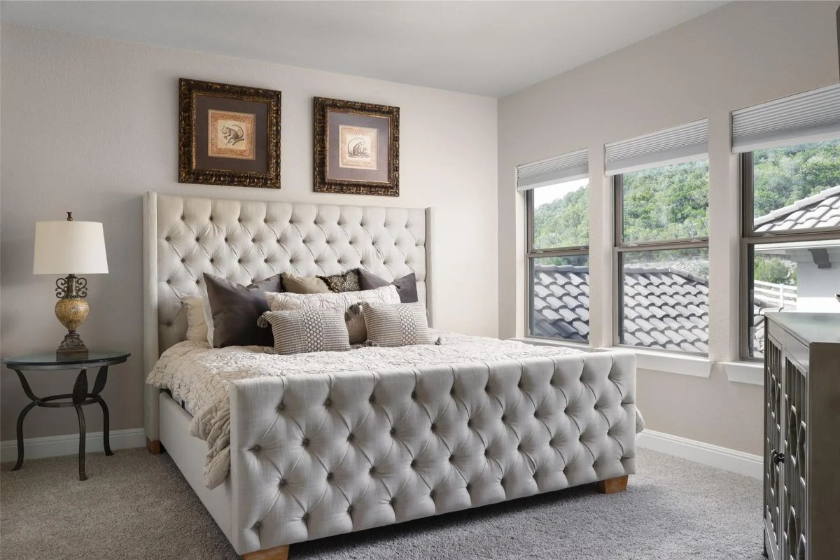 Tufted upholstered bed is centered on carpeted flooring.