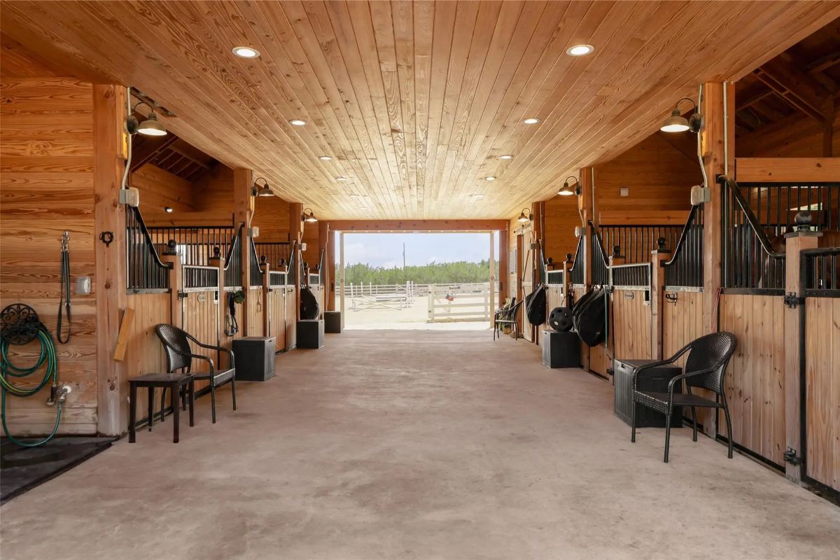 Central aisle is lined with horse stalls on both sides.