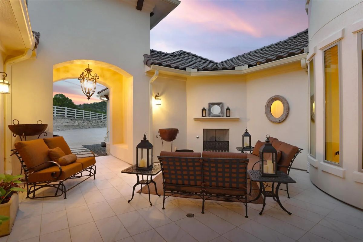 Outdoor fireplace is surrounded by cushioned lounge chairs and metal seating.