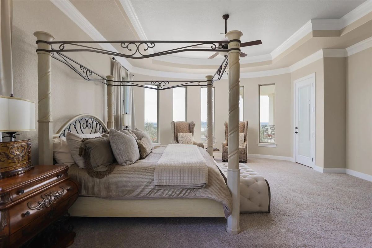 Four-poster bed centered between nightstands and seating area.