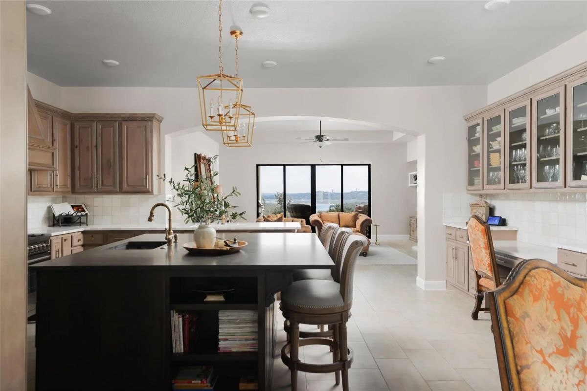Dark center island with bar seating faces open living area.
