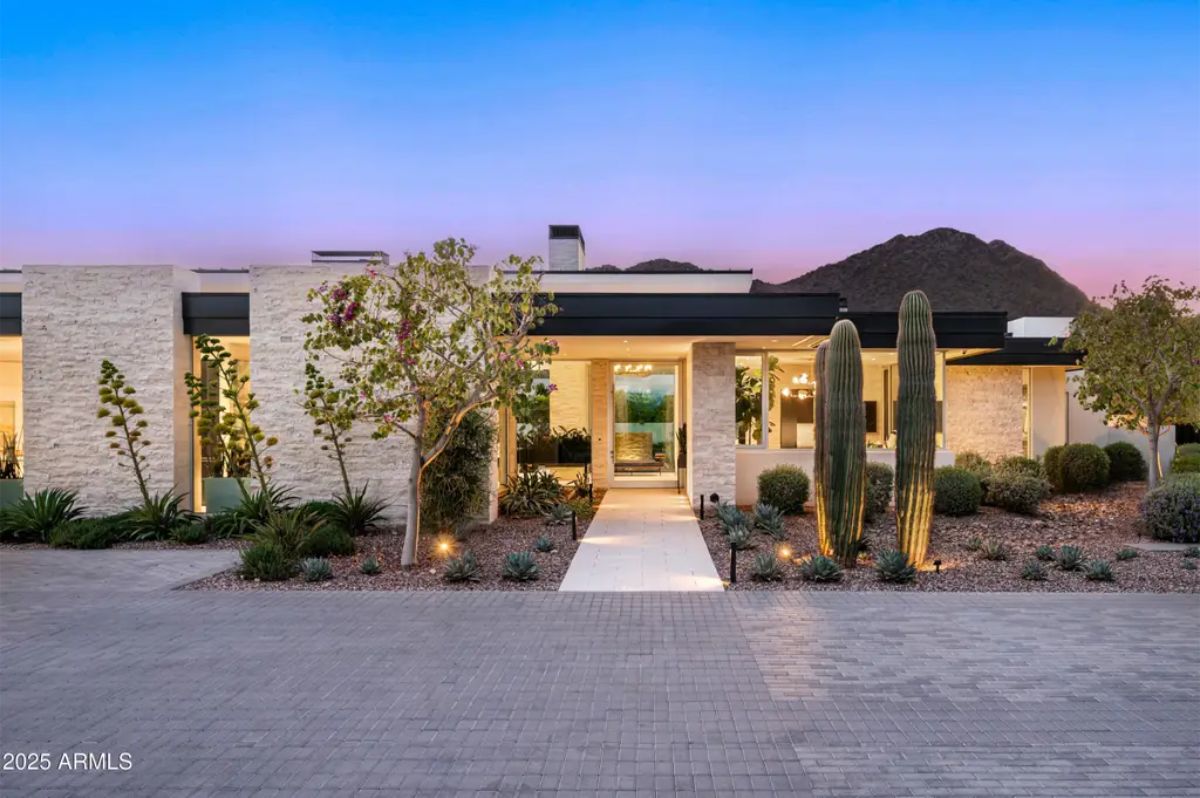 Desert landscaping frames the front entry of a contemporary residence with stone accents and Camelback Mountain backdrop. 