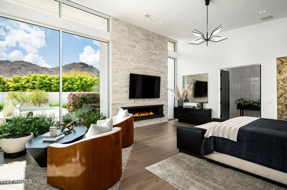 Primary bedroom combines mountain views, fireplace, and modern furnishings in a neutral palette. 