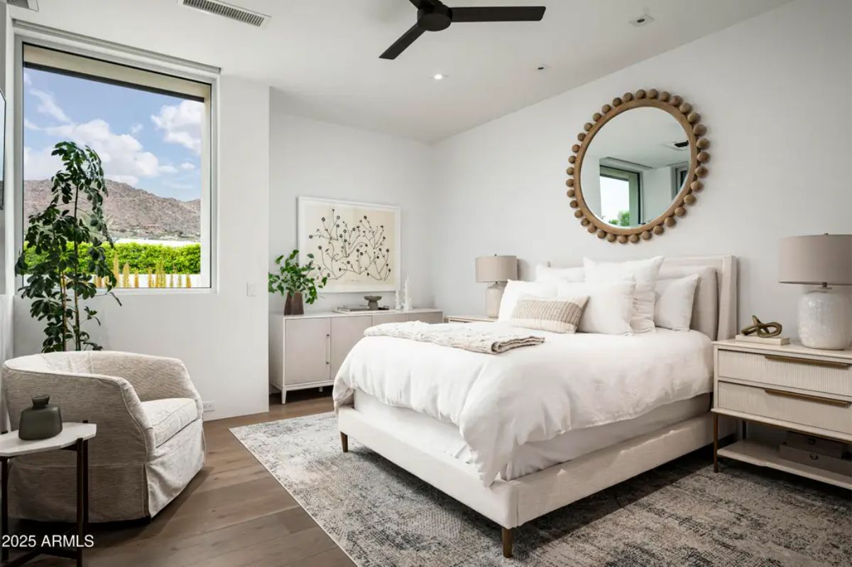 Guest bedroom with mountain-facing window features soft tones and plush bedding. 