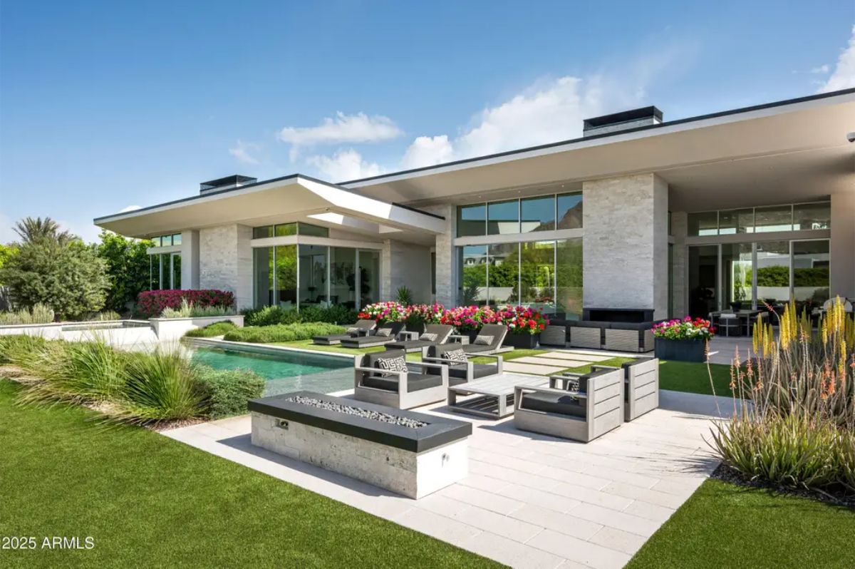 Backyard entertaining space with poolside seating, lush lawn, and modern architecture. 