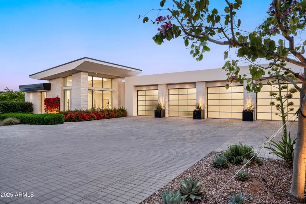 Front exterior with glass-panel garage doors, desert landscaping, and evening lighting. 
