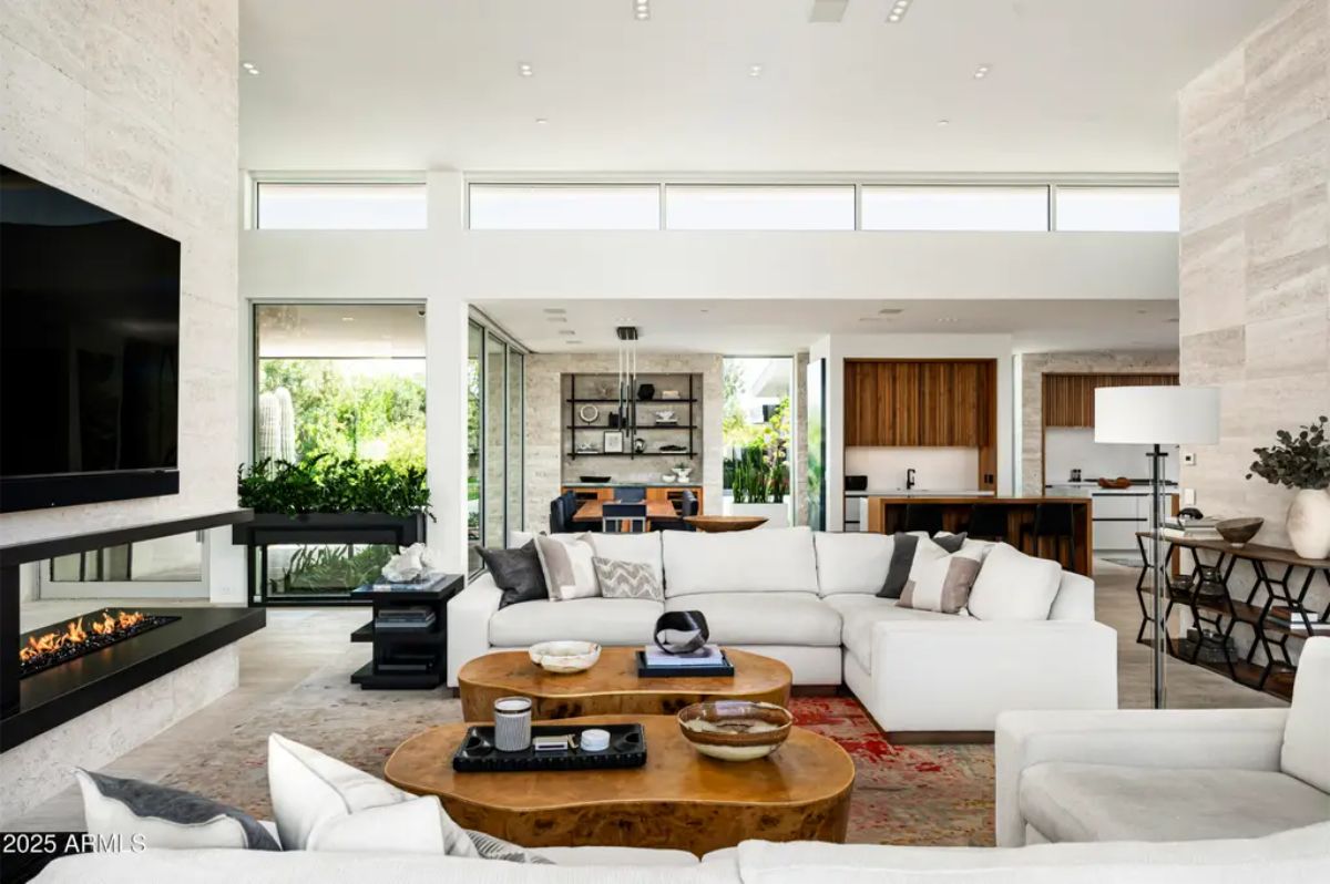 Open layout living space centers around a modern fireplace with neutral tones and layered textures. 