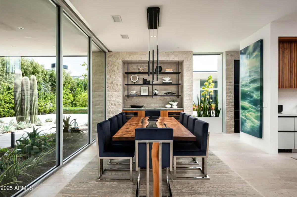 Dining area showcases a live-edge wood table, glass walls, and built-in shelving. 