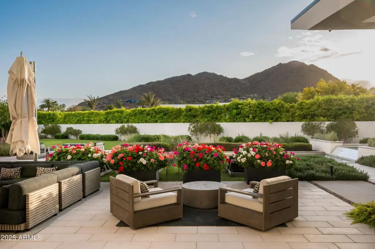 Outdoor seating area with circular firepit and mountain views framed by vibrant landscaping. 