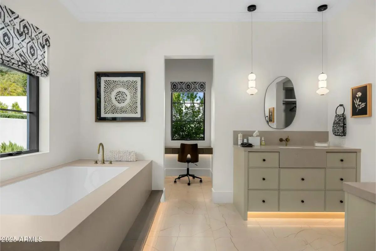 Spa-style bathroom with built-in tub, floating vanity, and a small nook leading to a workspace. 
