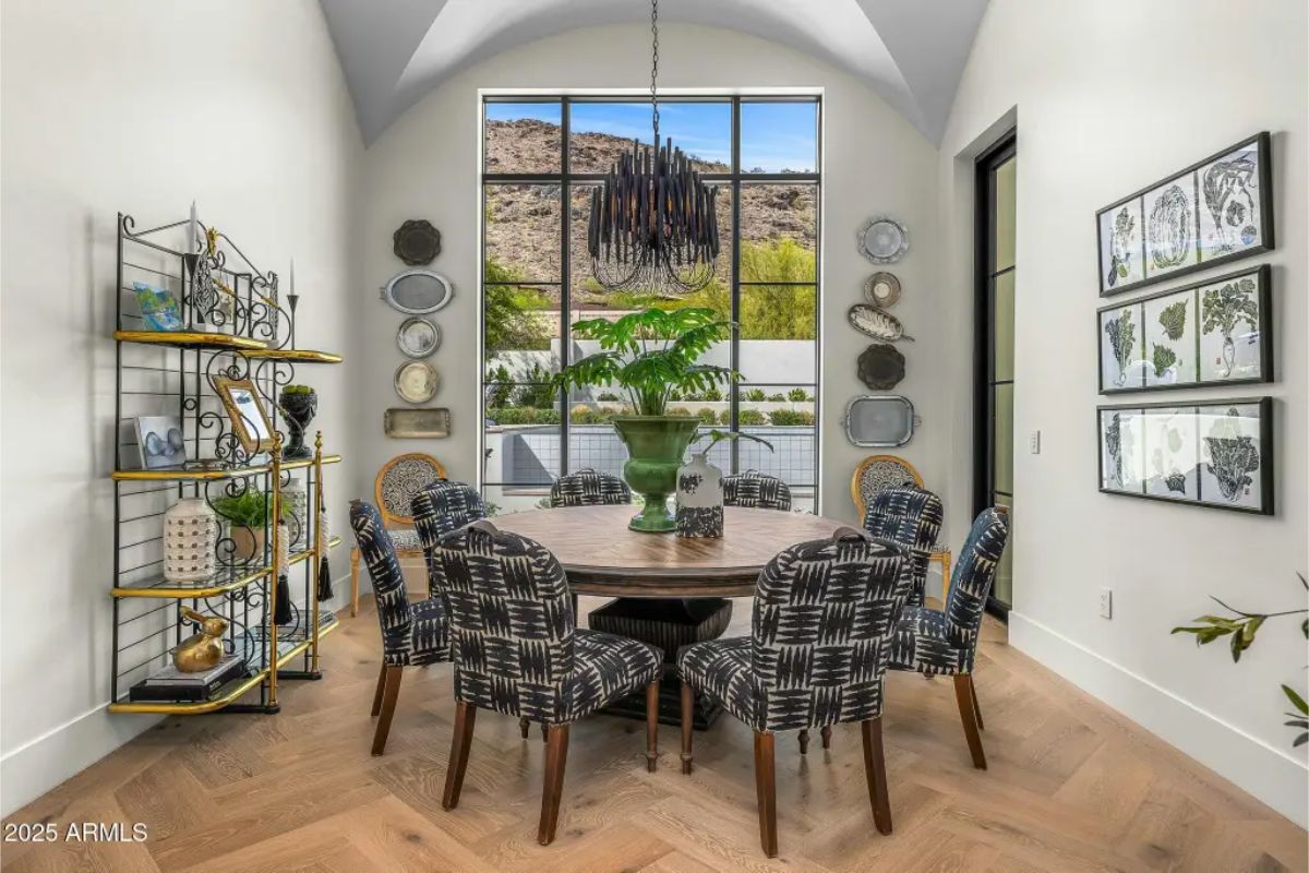Intimate dining room with plaid upholstered chairs, vaulted ceiling, and a picture window framing mountain views. 