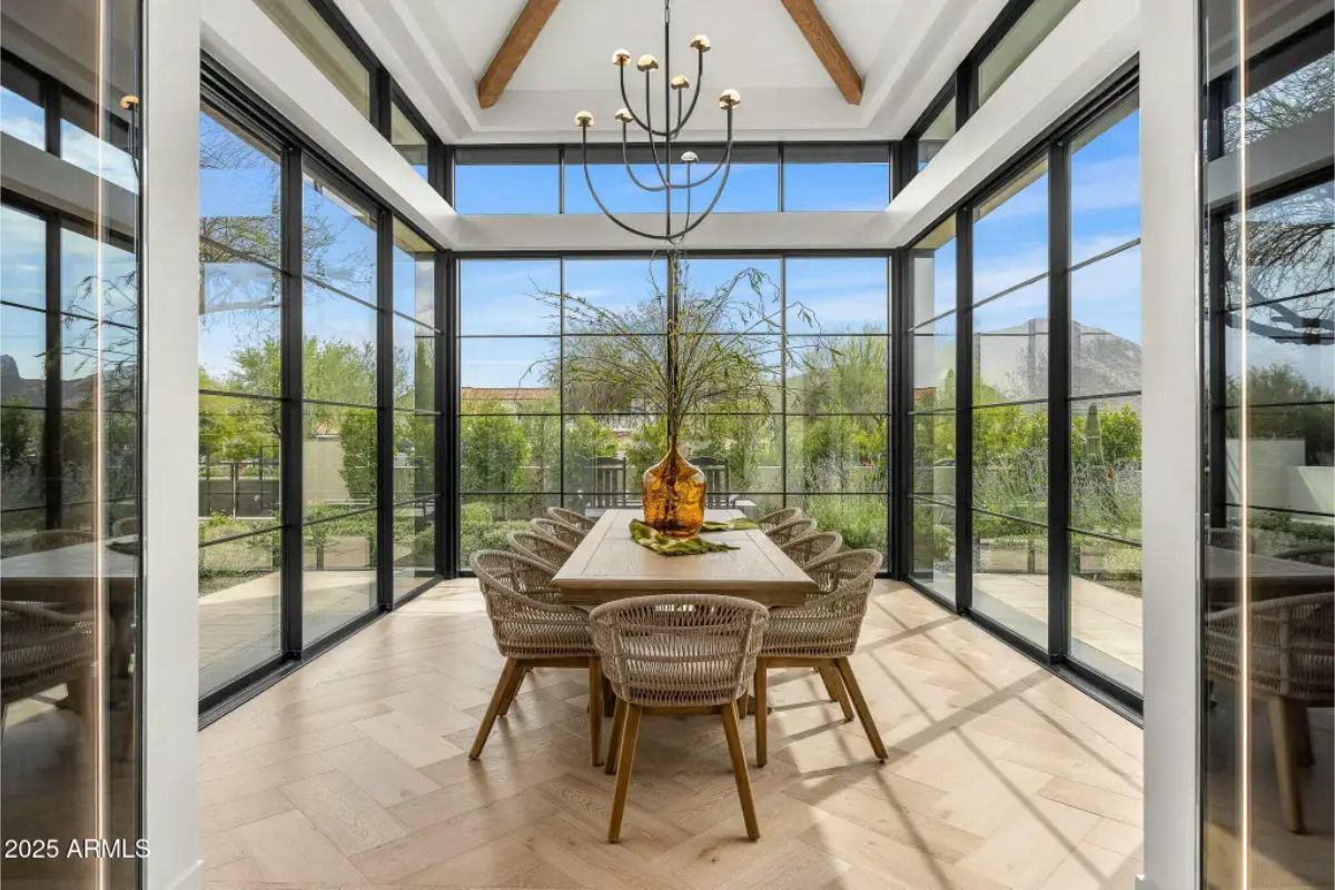Glass-wrapped dining area with wood beam ceiling, panoramic views, and natural light from every side. 