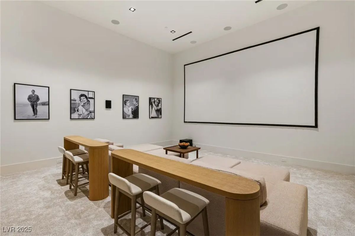 Home theater with tiered seating, built-in sofa, and wall-mounted screen. 
