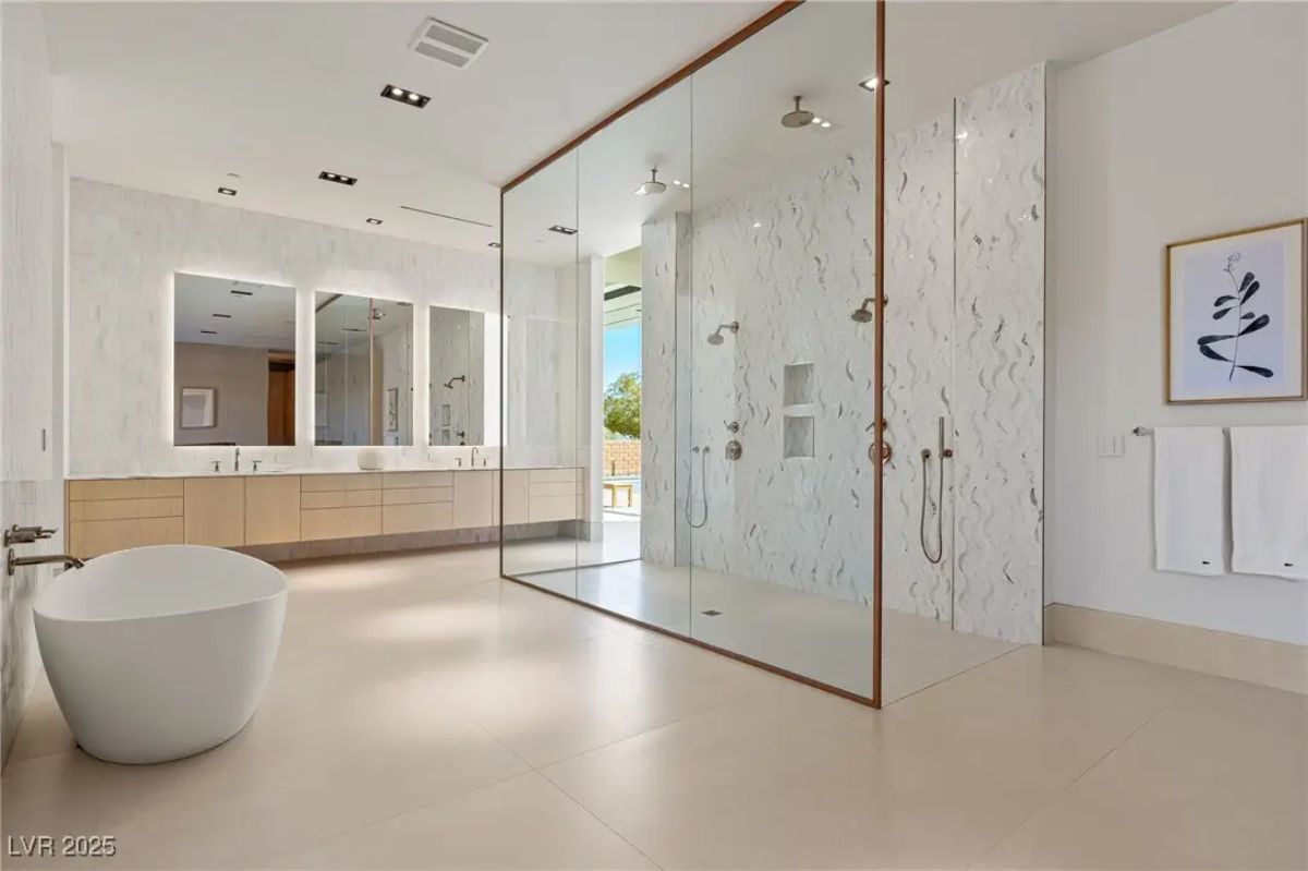 Modern bathroom with double vanity, freestanding tub, and large glass-enclosed shower. 