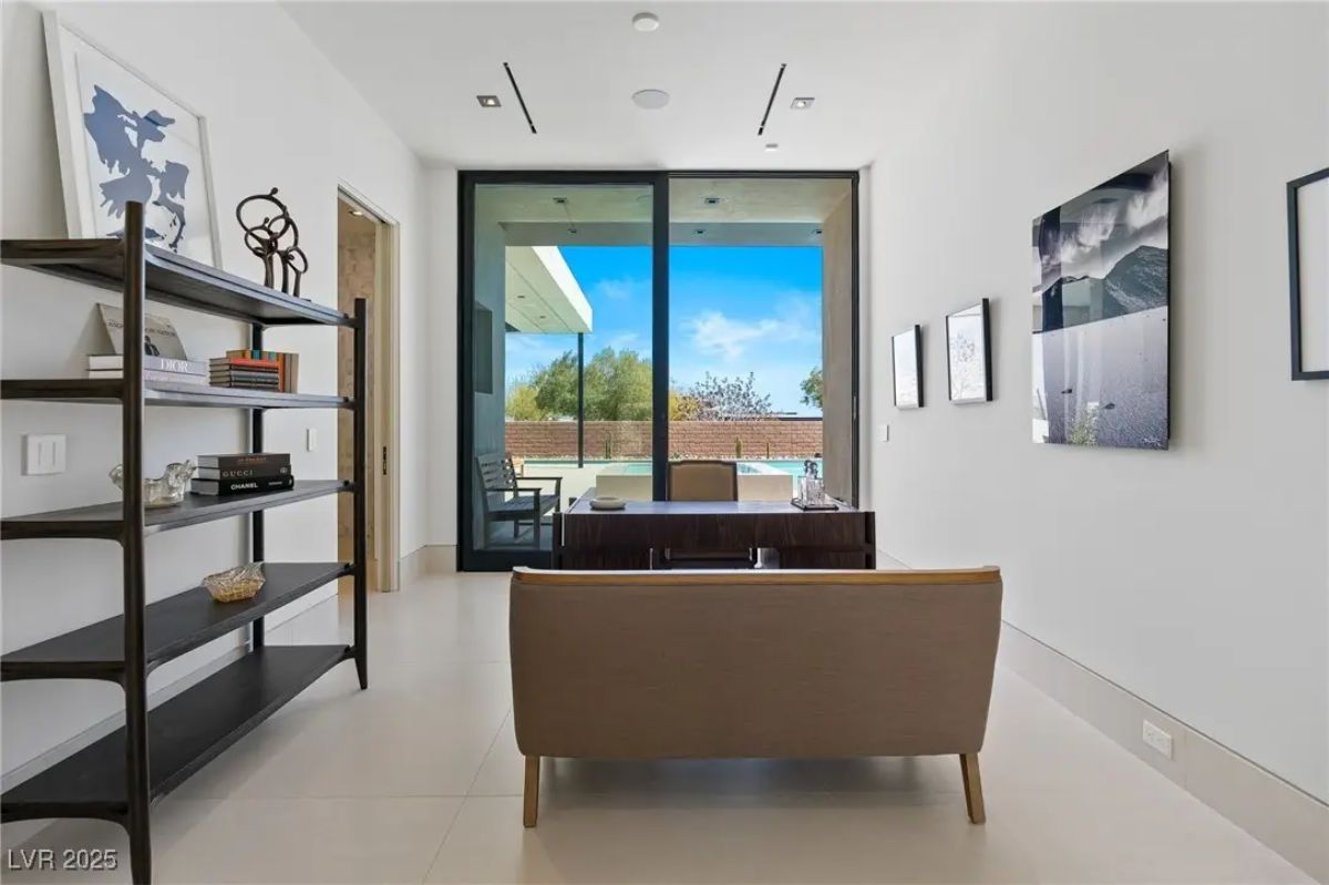 Home office with built-in shelving, desk facing glass doors, and gallery wall. 