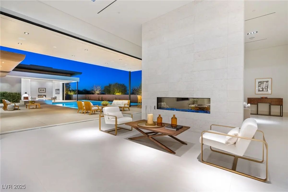 Sitting area with minimalist fireplace and views of outdoor living space. 