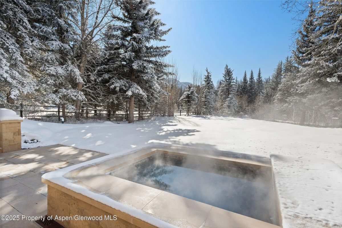 Outdoor hot tub steaming in a snow-covered forest setting. 