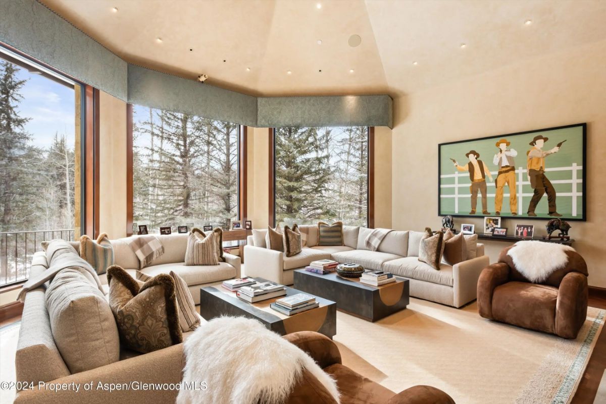 Living room with vaulted ceiling, large windows, and two plush sectional sofas facing each other. 