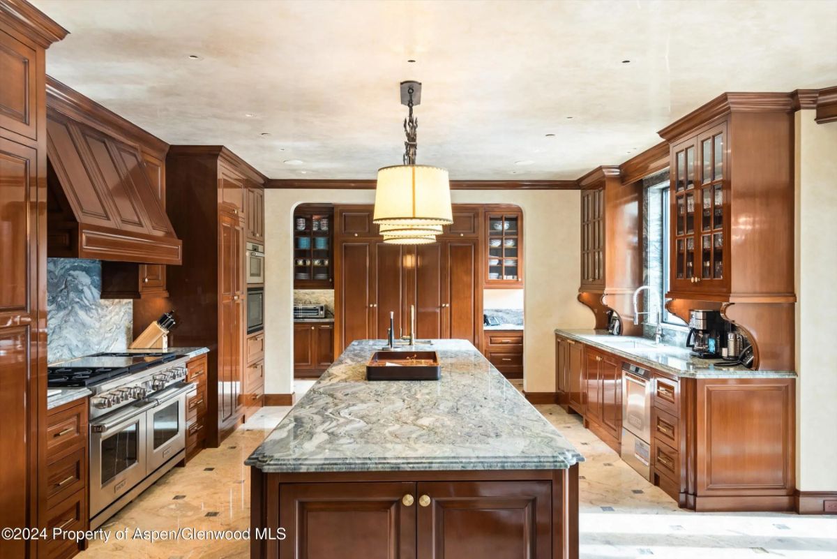 Spacious kitchen with double islands, dark wood cabinetry, and marble countertops. 