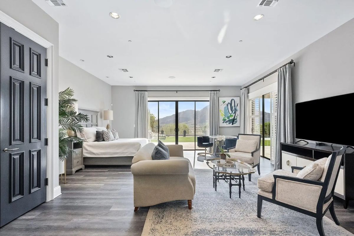 Bedroom suite with large sitting area, sliding glass doors, and mountain views beyond a private patio. 