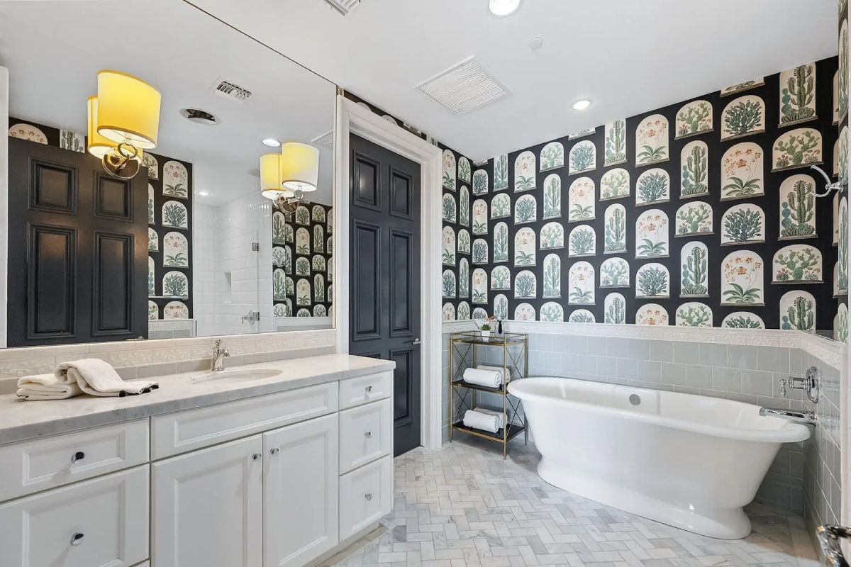 Guest bathroom with freestanding tub, patterned wallpaper, and bright white cabinetry. 