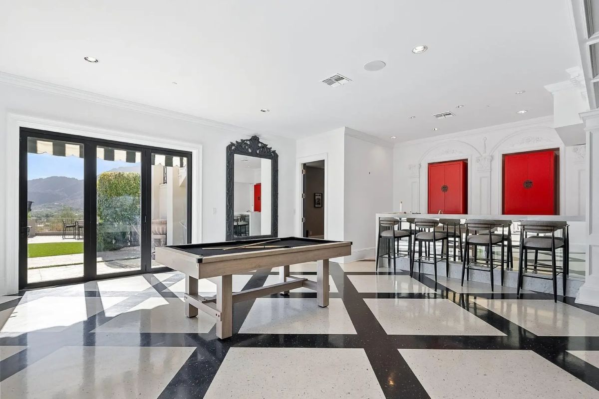 Game room and bar area with black-and-white tile flooring, pool table, and modern art accents. 