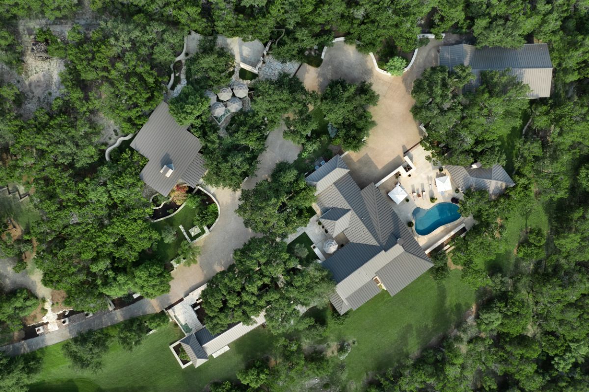 Aerial view of large estate with multiple structures nestled within dense forest. 