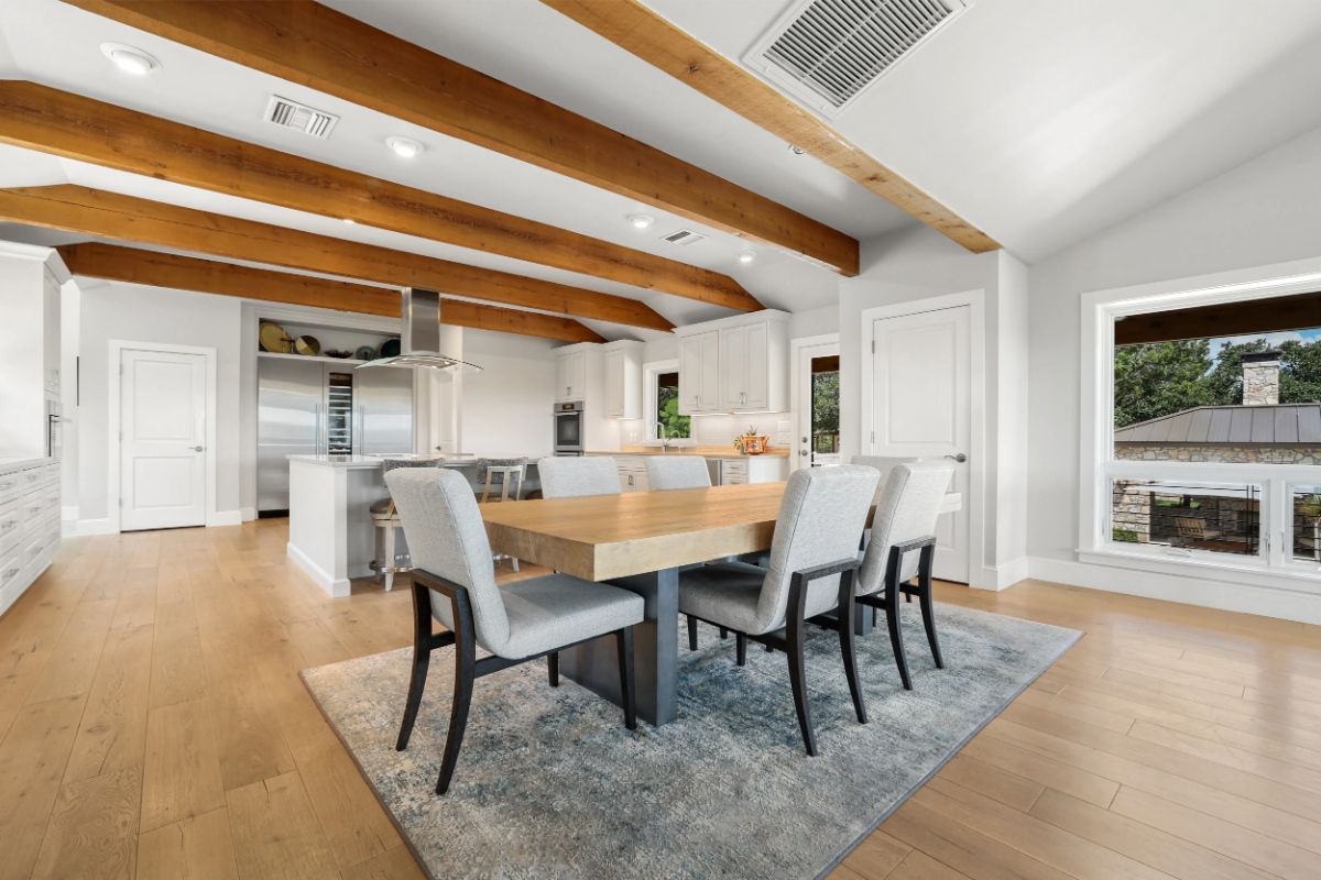 Open-concept kitchen and dining area with exposed ceiling beams and island seating. 