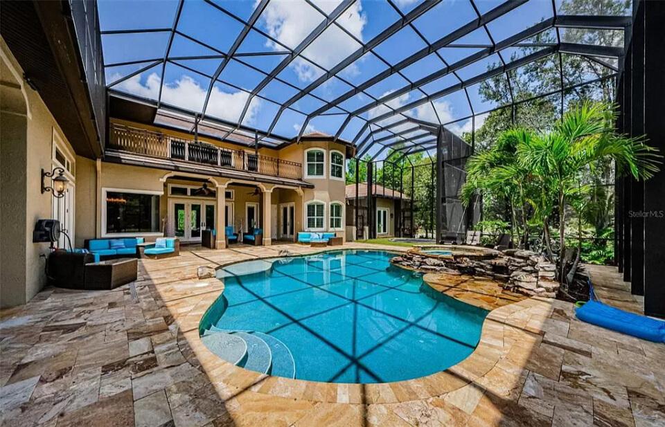 Experience Luxury in This Expansive Screened Pool Area with a Nature-Inspired Waterfall