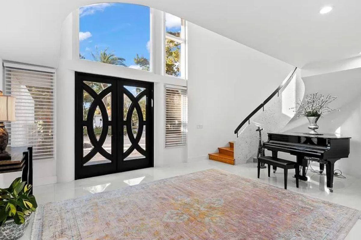Admire This Elegant Foyer with Curved Staircase and Grand Piano