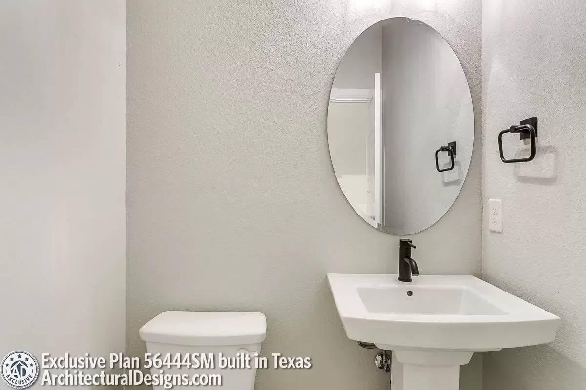 Sleek Powder Room with an Oval Mirror Adding a Touch of Modernity