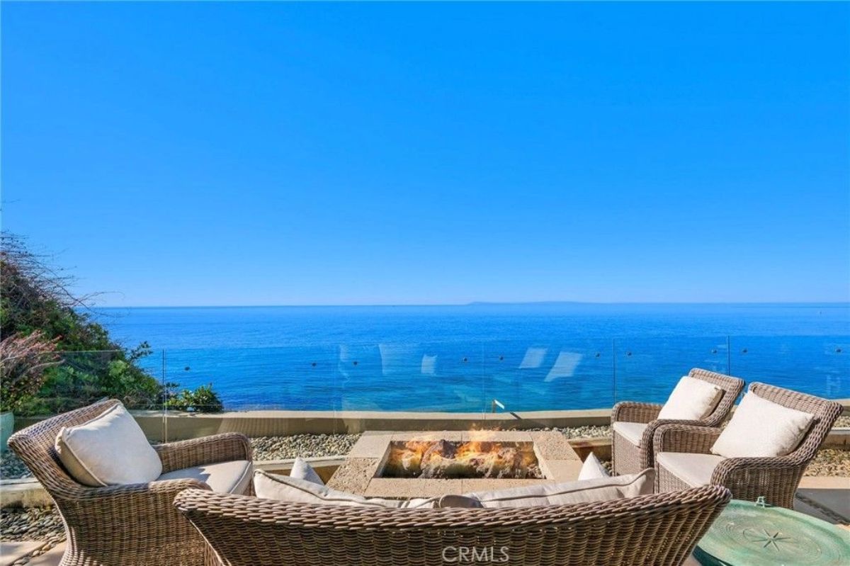 Four wicker armchairs surround a square fire feature overlooking the ocean.