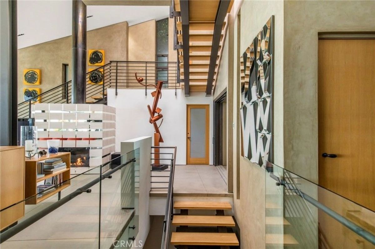 Floating stairs run alongside a corridor with glass railing and metal accents.