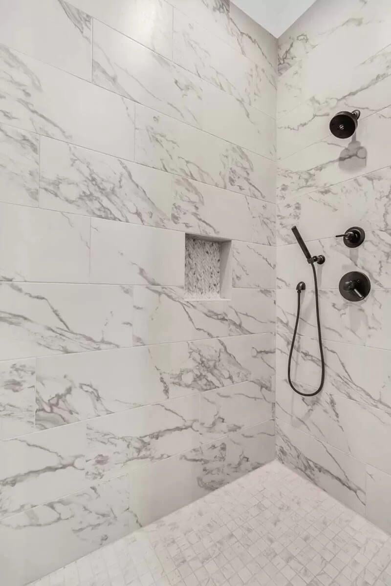 Notice the Bold Black Fixtures Against the Marble in This Shower